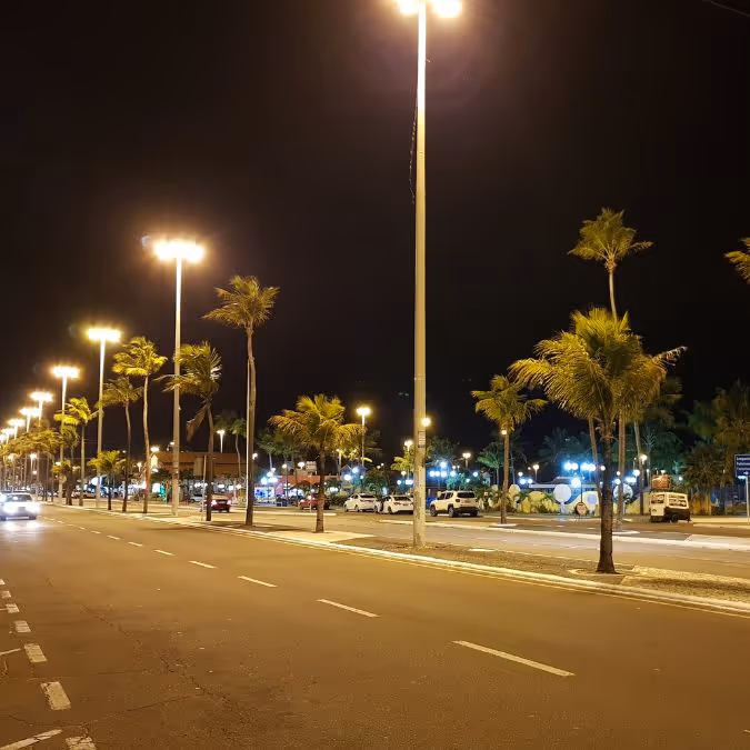 Avenida iluminada à noite em Aracaju, destacando a urbanização e o clima seguro da cidade
