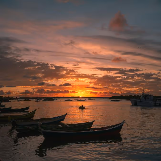 Pôr do sol em Aracaju com barcos ancorados, representando a beleza natural e a tranquilidade da cidade